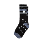 Pair of black crew socks with a grey stripe featuring upside-down white cats and scattered white paw prints. 