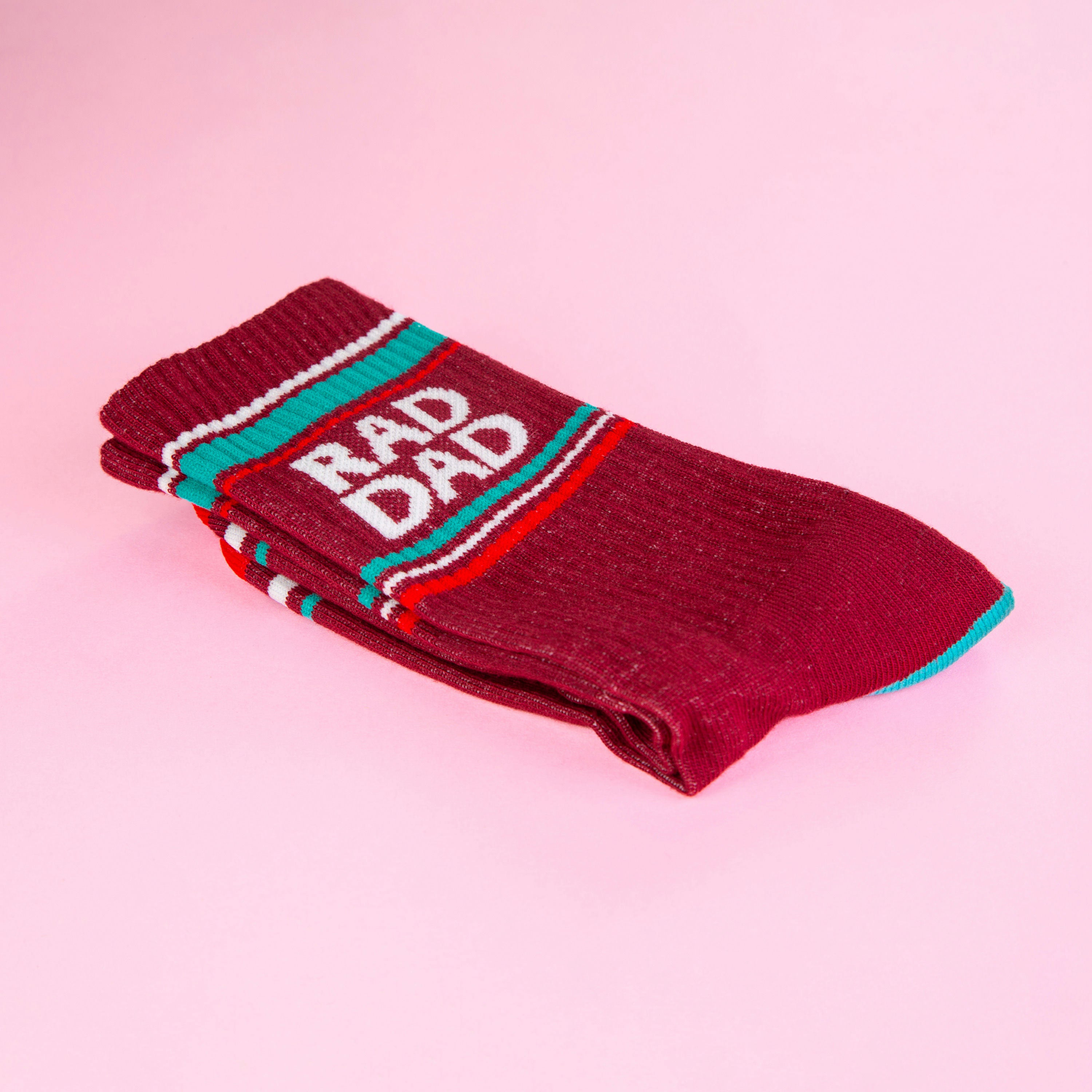 A folded maroon Rad Dad sock on a pink background, showcasing the folded texture and details. [lf]