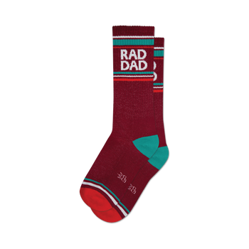 a pair of socks with the words 'rad dad' in large, white letters on a red background. socks that are dark red with white and teal stripes at the top and a red toe and heel.