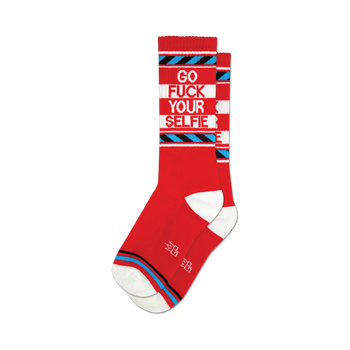 socks that are red with white toes and heels. they have a blue and white striped pattern around the top and a blue and white striped pattern around the ankle. the words "go fuck your selfie" are written in white on the front of the socks.