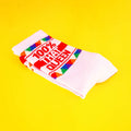 Close-up of the folded '100% That Queen' socks on a yellow background. [lf]