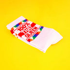 Close-up of the folded '100% That Queen' socks on a yellow background. [lf]