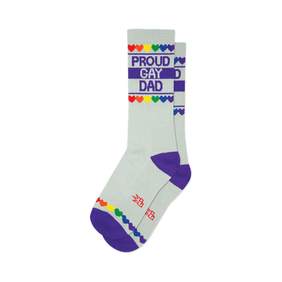 front view of a pair of gray socks with a rainbow heart and purple stripe pattern and the words "proud gay dad".