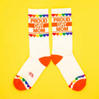 Another flatlay shot of the 'Proud Gay Mom' socks on a yellow background. Socks laid parallel. [lf]