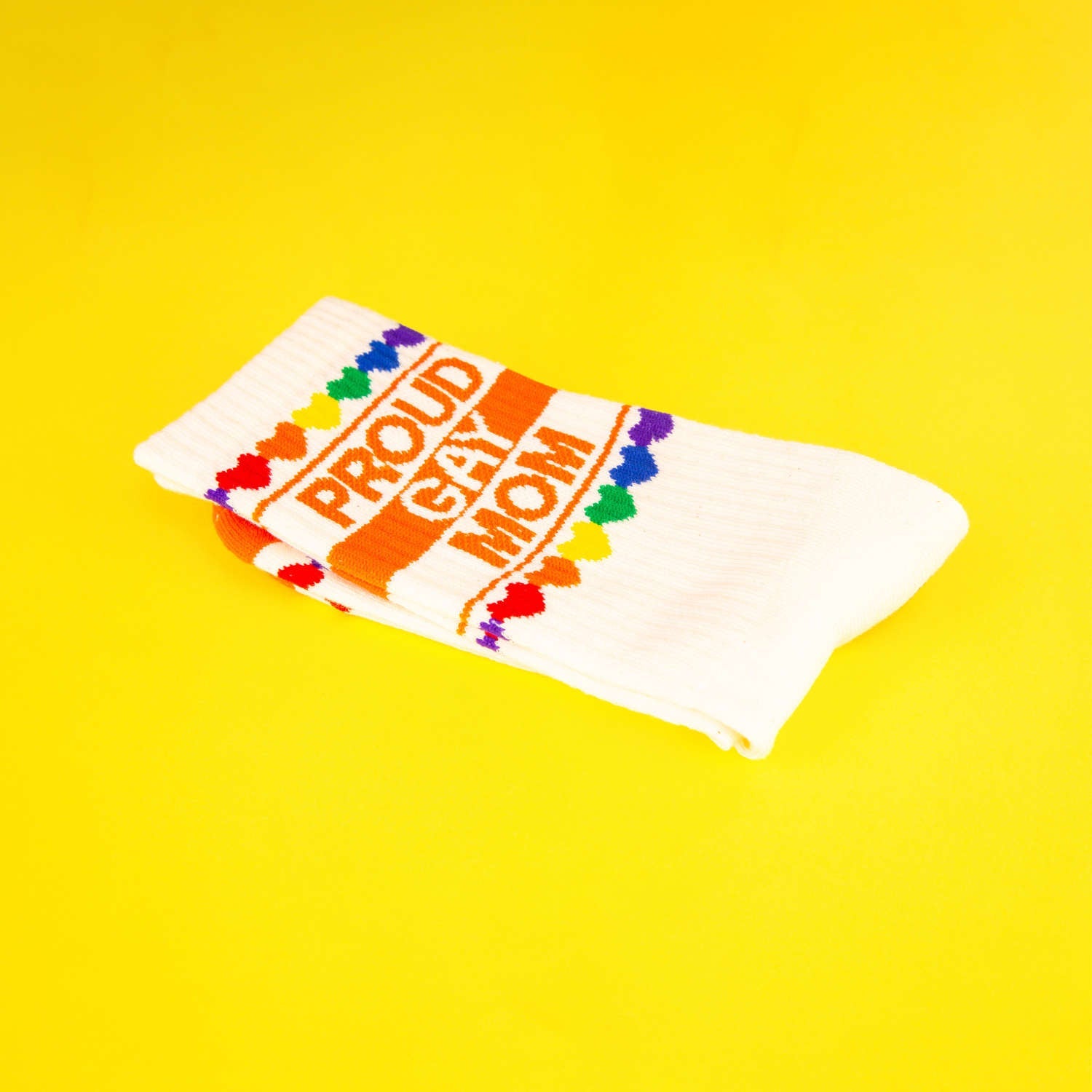Close-up of folded 'Proud Gay Mom' socks on a yellow background. [lf]