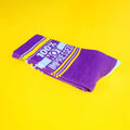 Close-up of a single purple '100% Not Impressed' sock folded on a yellow background. [lf]