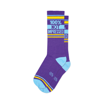 front view of two purple socks with blue and yellow stripes and the words "100% not impressed" printed on them.