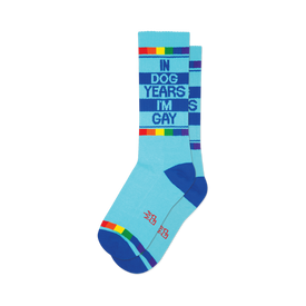 front view of a pair of blue teal gym socks that say "in dog years i'm gay" with a rainbow stripe.