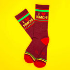 Flat lay of maroon 'I heart kimchi' socks against a yellow background.