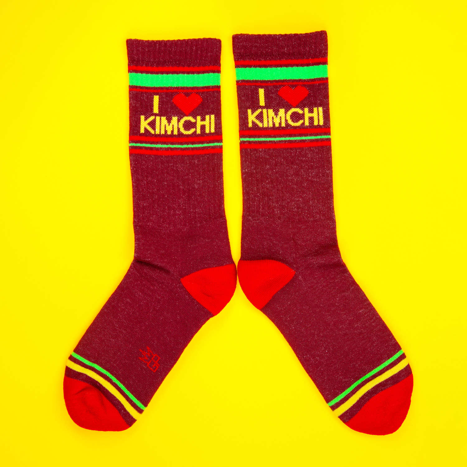 Another flat lay of maroon 'I heart kimchi' socks, laid flat on a yellow background.