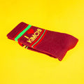 Close-up of folded maroon 'I heart kimchi' socks on a yellow background.