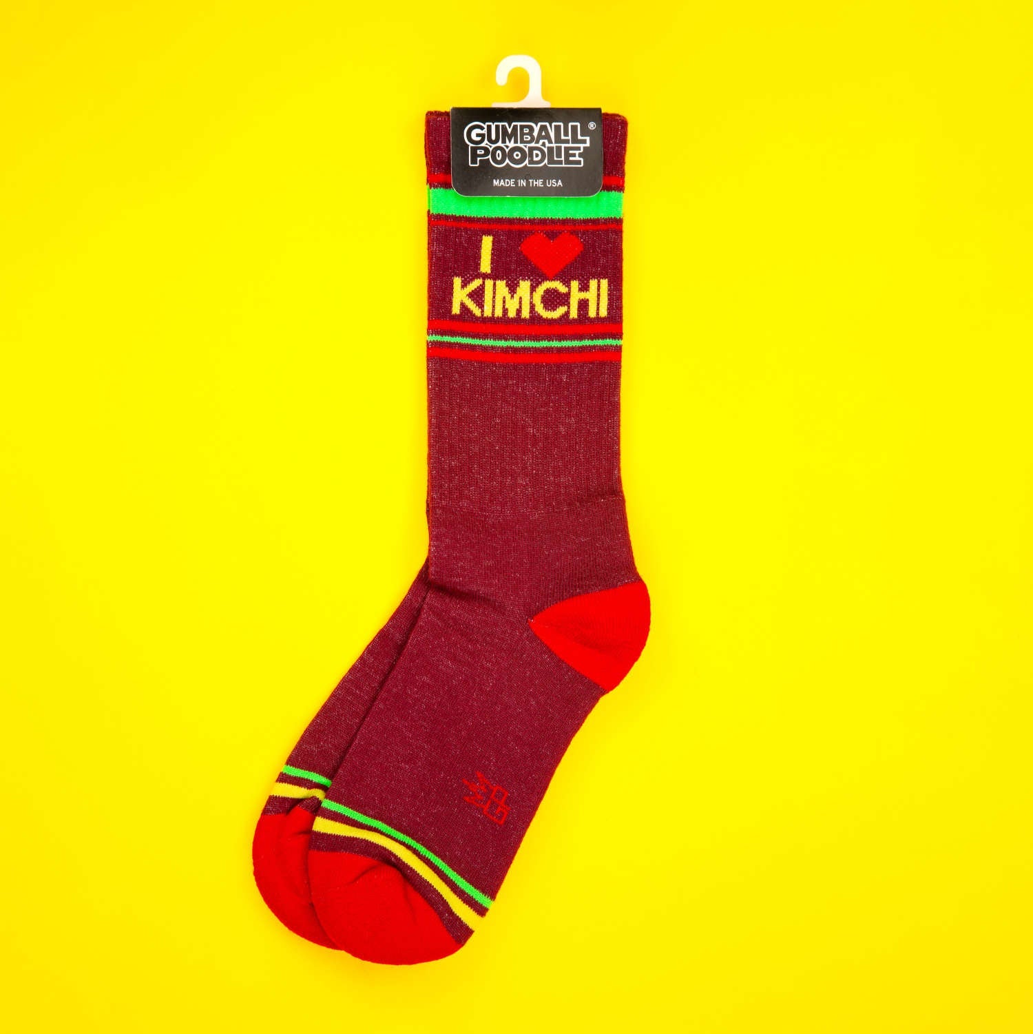 Maroon 'I heart kimchi' socks on a yellow background, displayed on a hanger.