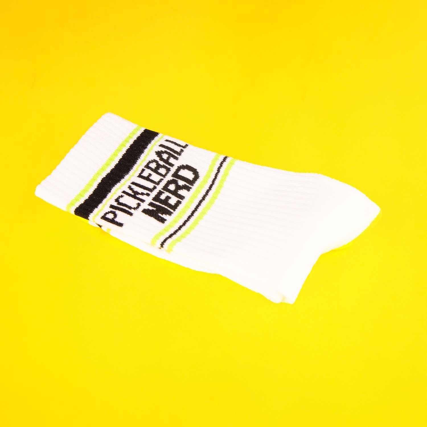Close-up of a single Pickleball Nerd sock on a yellow background. [lf]