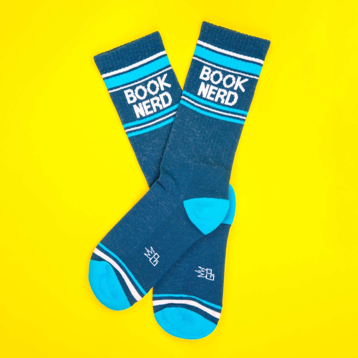 Flatlay of teal 'Book Nerd' socks on yellow background. [lf]