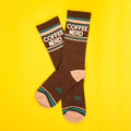 Flatlay product shot of a pair of brown Coffee Nerd socks on a yellow background. [lf]