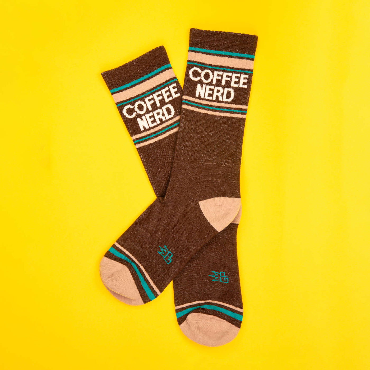 Flatlay product shot of a pair of brown Coffee Nerd socks on a yellow background. [lf]