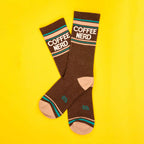 Flatlay product shot of a pair of brown Coffee Nerd socks on a yellow background. [lf]