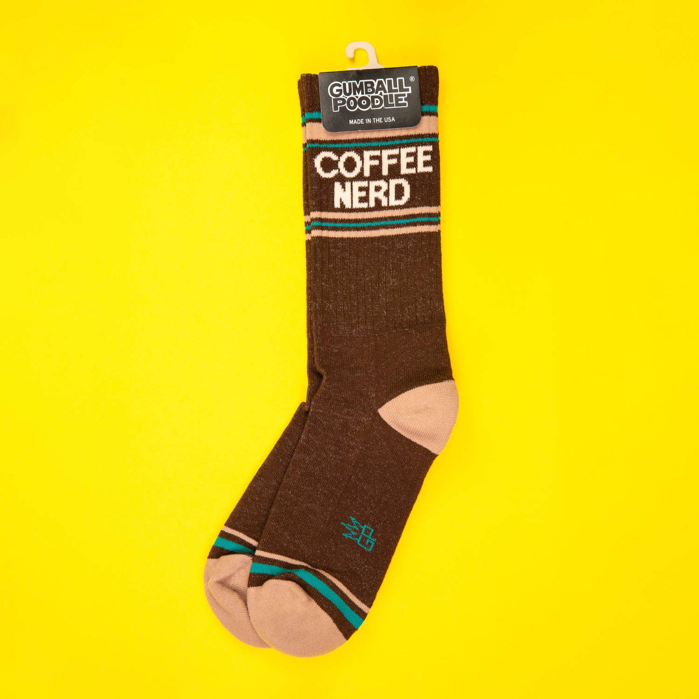 Single brown Coffee Nerd sock hanging on yellow background, showcasing the Gumball Poodle tag. [lf]