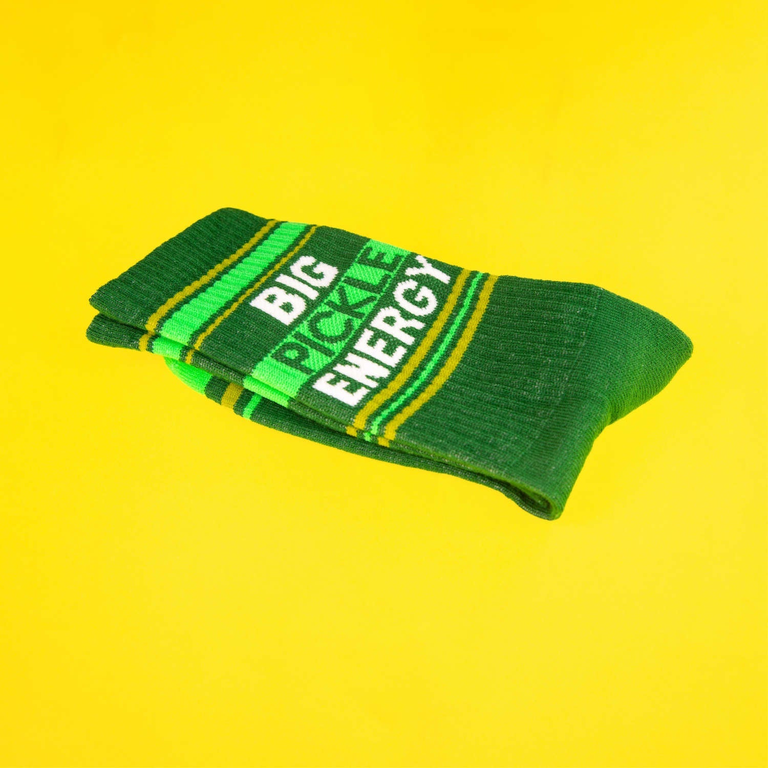 A folded green 'Big Pickle Energy' sock on a bright-yellow background. [lf]