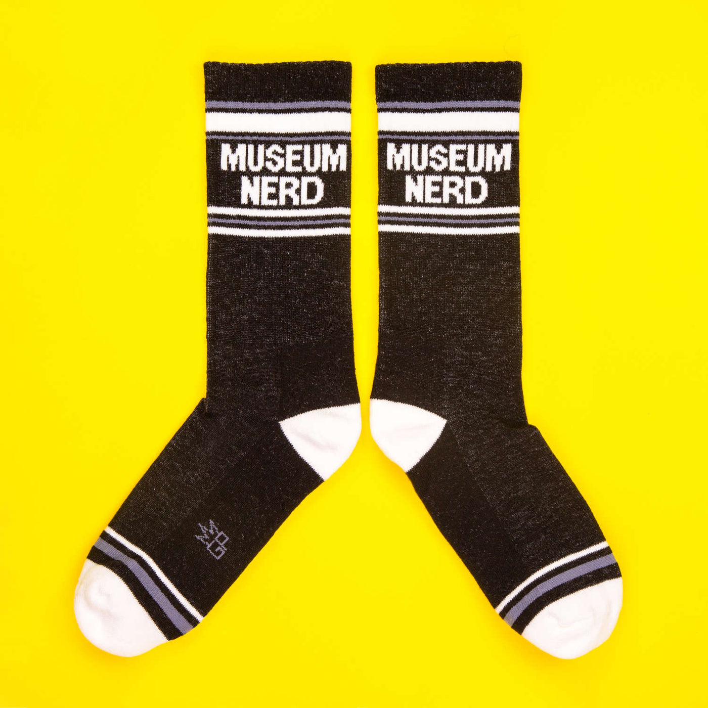 Museum Nerd socks laid out on a yellow background; showcasing both socks. [lf]