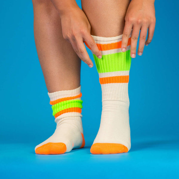 Lifestyle shot: Person putting on a Bobby sock, highlighting the fit and feel against a blue background. [lf]