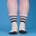 Detail shot highlighting the fabric texture and striped design of the off-white crew socks with black and grey stripes. [lf]