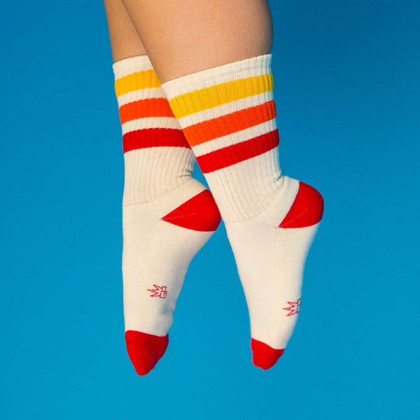 Lifestyle shot: Tiger socks on feet against a bright blue background. [lf]