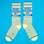 Another flatlay of two 'Easily Distracted By Birds' socks, arranged differently, on a bright blue background. [lf]