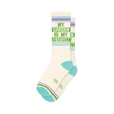 front view of a pair of white socks with green and purple stripes that say "my garden is my therapist".