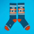 Another flat lay of teal 'The Library Is My Therapist' socks on a blue background. [lf]