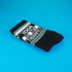 Folded 'Yoga Is My Therapist' socks on a vibrant blue background. [lf]