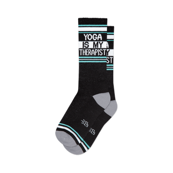 front view of a pair of black socks with the words 'yoga is my therapist' in white letters.