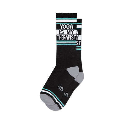 front view of a pair of black socks with the words 'yoga is my therapist' in white letters.