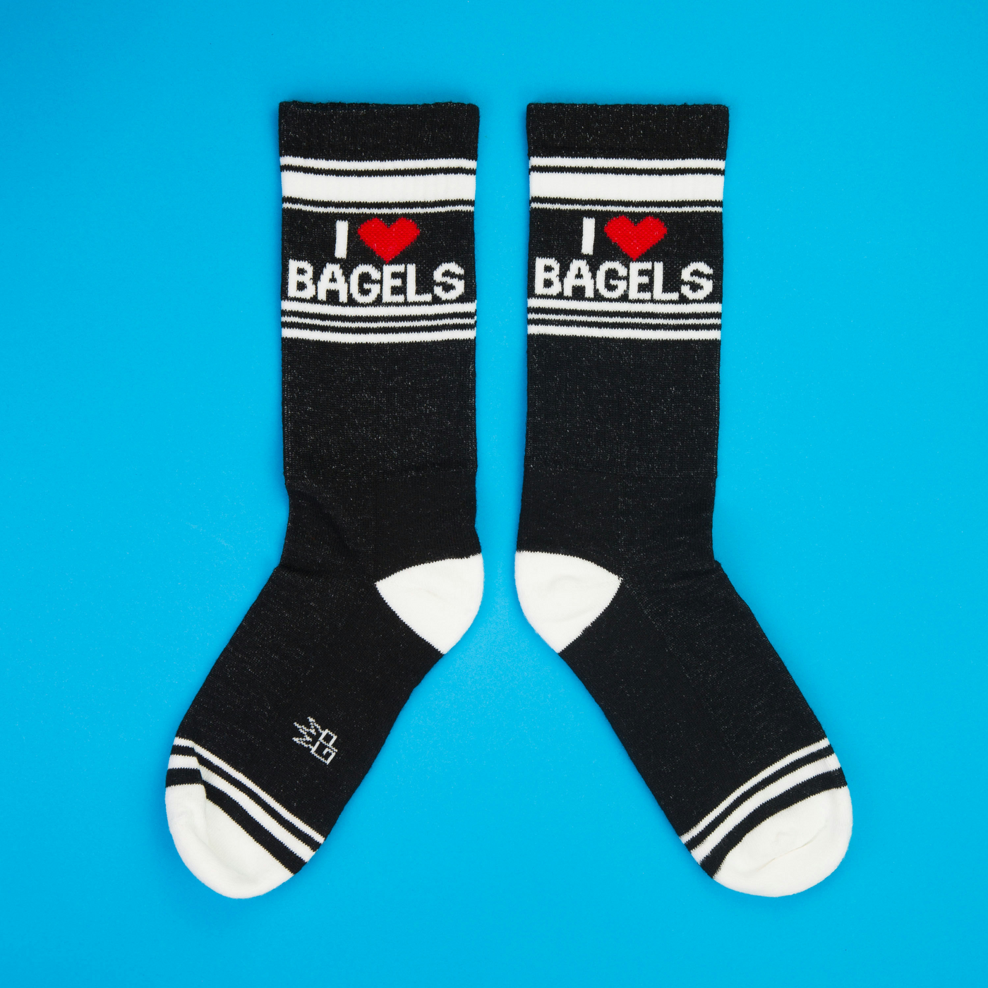 Another flatlay showcasing the 'I Heart Bagels' socks, arranged in a different position on a blue background.