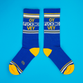 Flatlay product shot of a pair of 'Oy Fucking Vey' socks on a bright blue background.