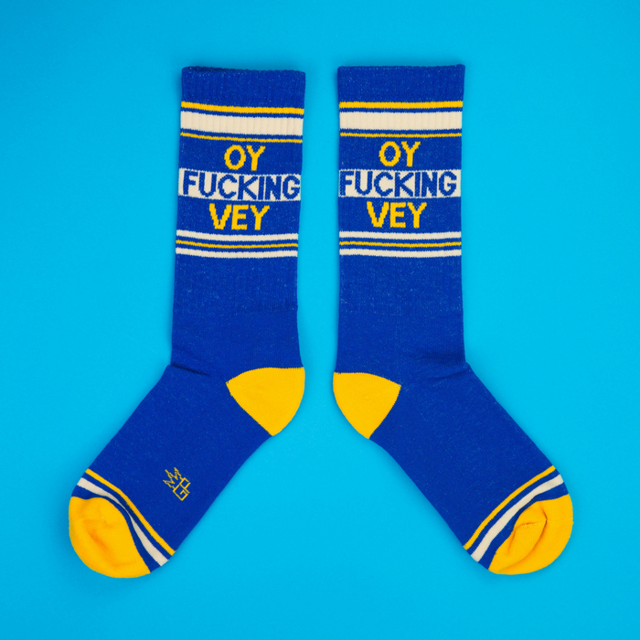 Flatlay product shot of a pair of 'Oy Fucking Vey' socks on a bright blue background.