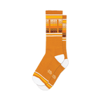 Pair of mustard yellow crew socks with horizontal stripes that say 'Beer' in a retro style font.  White and orange accents.