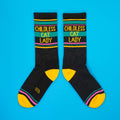 Flat lay product shot of 'Childless Cat Lady' socks on a bright blue background. [lf]