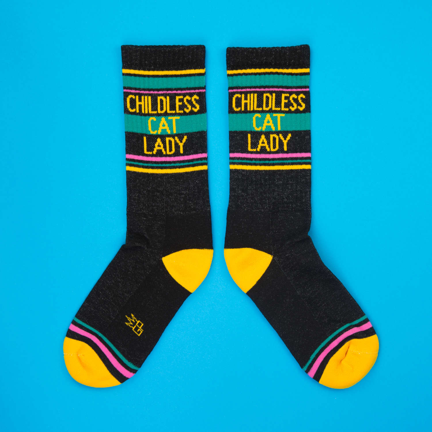 Flat lay product shot of 'Childless Cat Lady' socks on a bright blue background. [lf]