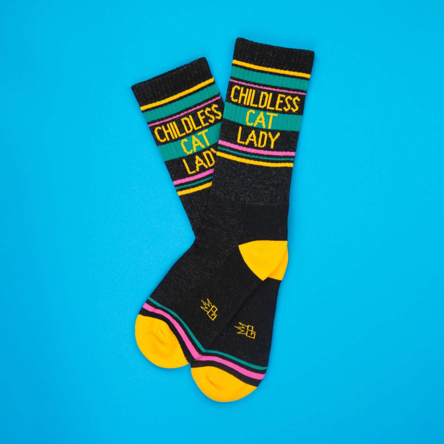 Lifestyle product shot of 'Childless Cat Lady' socks, slightly angled on a bright blue background. [lf]