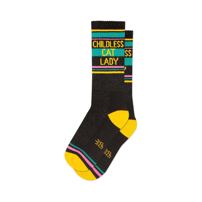 front view of two black socks with yellow, pink, and teal stripes that read 'childless cat lady'.