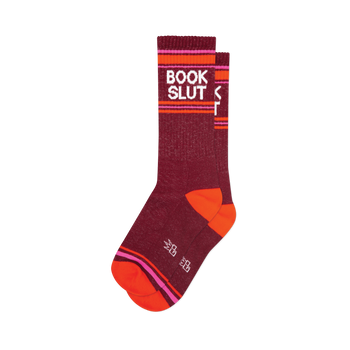 Dark red "Book Slut" crew socks featuring white text, vibrant pink & orange stripes, plus bright orange heels/toes.