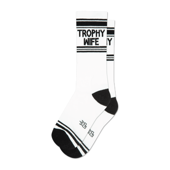 A pair of white crew socks with black stripes and the words 'Trophy Wife' in black.  The socks have a black heel and toe.