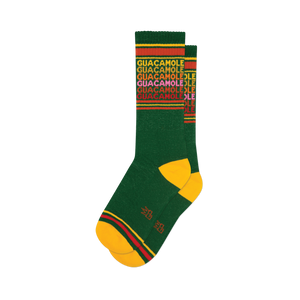 Pair of green crew socks with a repeating 'Guacamole' pattern in yellow, red, and pink. Yellow and red stripes at the top and bottom.