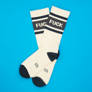 Flat lay of a pair of 'F*ck' socks on a bright blue background.