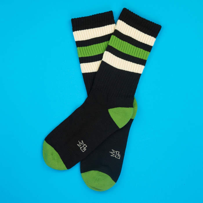 Elroy Retro socks on a blue background, showcasing the green and off-white stripes.