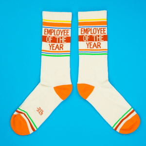 Flatlay product shot of a pair of 'Employee of the Year' socks on a bright blue background.