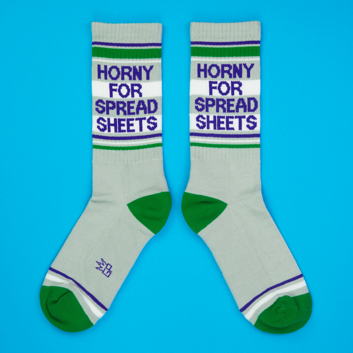 Flatlay product photo: Two 'Horny for Spreadsheets' socks on a bright blue background, arranged to showcase the design clearly.