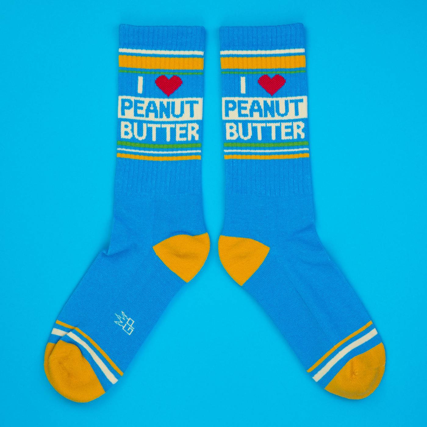 Flatlay product shot of two 'I Heart Peanut Butter' socks on a blue background.