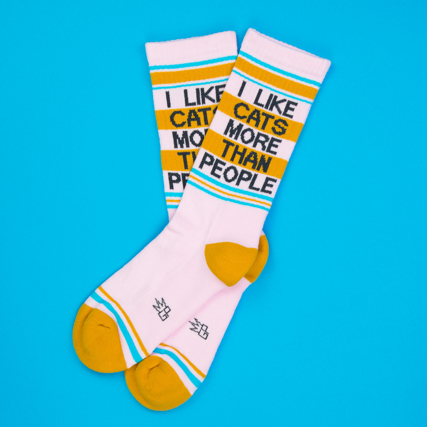 Lifestyle shot of two 'I Like Cats More Than People' socks on a blue background.